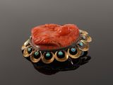 an antique carved coral and turquoise stone broochle on a black surface