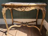 une petite table avec un plateau en marbre sur un plancher en bois