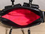 a black purse with red lining sitting on a wooden table