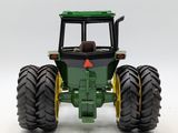 a green toy tractor with large tires on a white surface