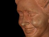 a clay bust of a man with a smile on his face