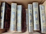 several old books are in a cardboard box on a table