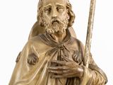 statue of a man holding a stick and wearing a cape