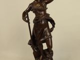 an antique bronze statue of a woman holding a bird on a wooden base