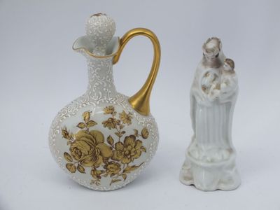 un vase blanc et doré et une figurine sur fond blanc