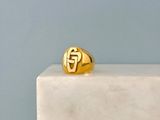 a gold signet ring sitting on top of a marble block