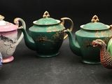 five different teapots sitting on a black surface