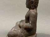 statue of a seated buddha on a rock on a gray background