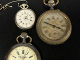 trois types différents de montres de poche exposées sur un fond noir