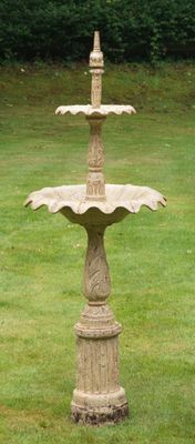 un oiseau perché au sommet d'une fontaine, dans l'herbe