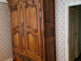 a wooden armoire in the corner of a room with floral wallpaper