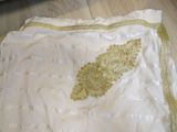 a white dress with gold embroidery on it on a wooden floor