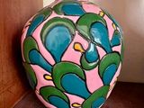 un vase rose et vert posé sur une étagère contre un mur