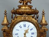 a gold clock sitting on top of a wooden table