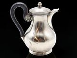 une théière ancienne en argent, dotée d'une anse noire sur un fond noir
