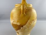 a yellow vase with a bird on top of it