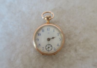 une montre de poche en or au cadran blanc posée sur une table