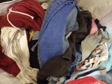 a pile of clothes that is sitting on a bed
