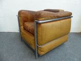 a brown leather chair with a metal frame on the floor