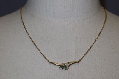 Collier plaqué or orné de pierres vertes et blanches, présenté autour du cou d'un mannequin