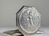 une image représentant une assiette en argent sur laquelle figurent une dame et un oiseau