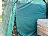 une tente verte située à côté d'un tas de bois