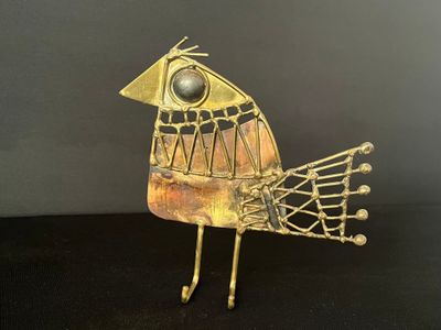 sculpture d'oiseau en métal doré posée sur une surface noire, avec un fond noir