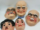six masks of men with different facial expressions on a white surface