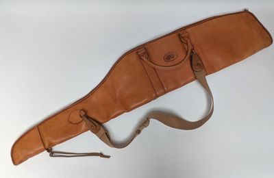 an old leather gun case hanging on a wall with a strap