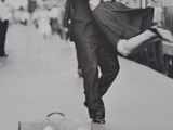 black and white photograph of a woman with a suitcase on the platform of a train station