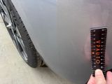 a person holding a measuring tape to measure the front of a car