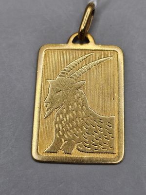 a close up of a gold pendant with a bird on it