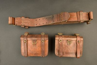 trois morceaux de cuir marron munis de boucles en laiton sur un fond gris
