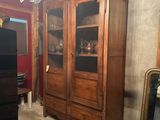 a large wooden cabinet in the middle of a room with a chandelier