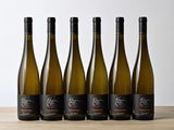 six bouteilles de vin blanc alignées sur une table en bois