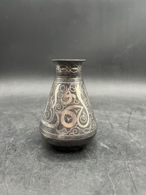 an old silver vase with a design on it sitting on a table