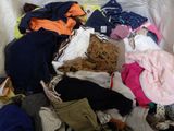 a pile of clothes that is sitting on a bed