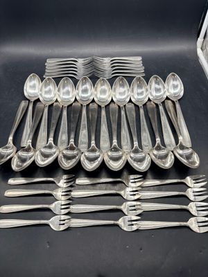 de nombreuses cuillères et fourchettes en argent sur une table noire