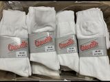 quatre paires de chaussettes blanches se trouvent dans une boîte posée sur une table