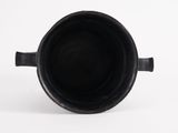 a black cup that is sitting on a white surface