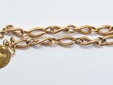 a close up of a gold chain bracelet with a coin on it