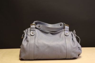 the gray purse is sitting on a table with a black background
