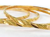 three gold rings on a white surface with a white background