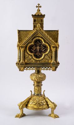 une horloge en or posée sur un socle surmonté d'une croix