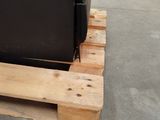 a black refrigerator sitting on a pallet in a warehouse
