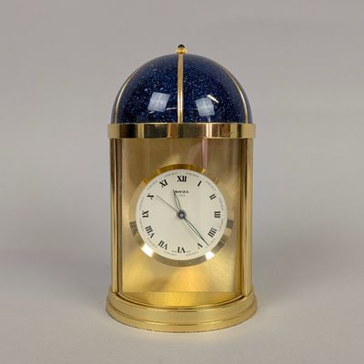 a gold clock with a blue glass dome on top