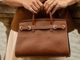 une femme qui tient un sac marron à la main