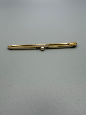 an image of a gold pin with a pearl on it