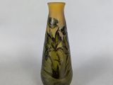 yellow and green glass vase with flowers on it on a white surface