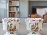 two vases sitting on a table in front of a bookshelf